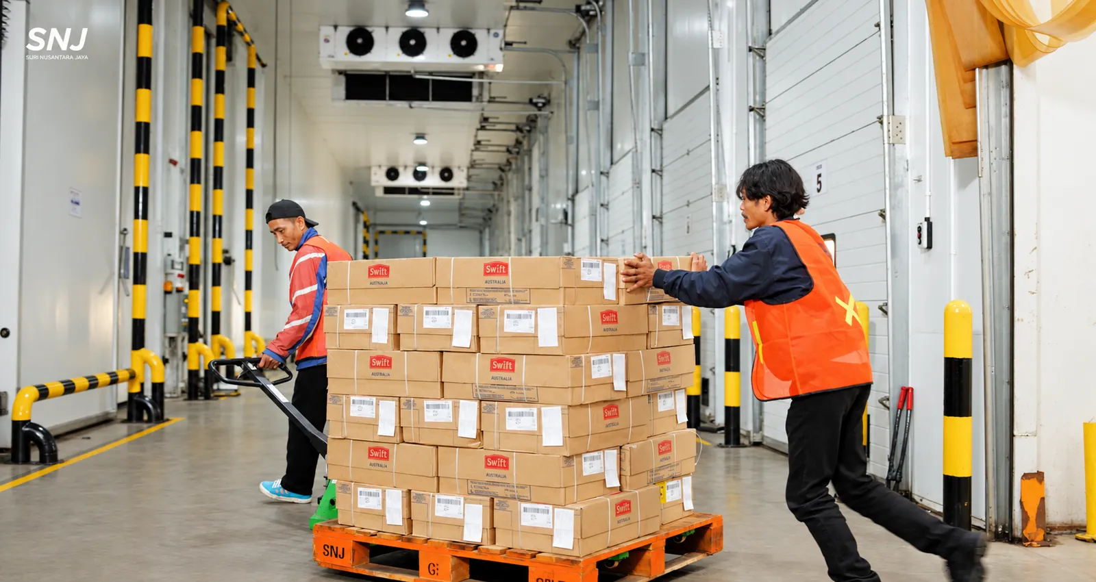 Tim handling SNJ memindahkan pallet produk di area loading cold storage